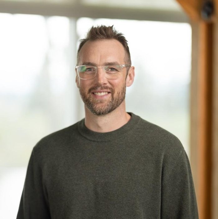Headshot of an IGVhousing team member in a grey sweater and glasses